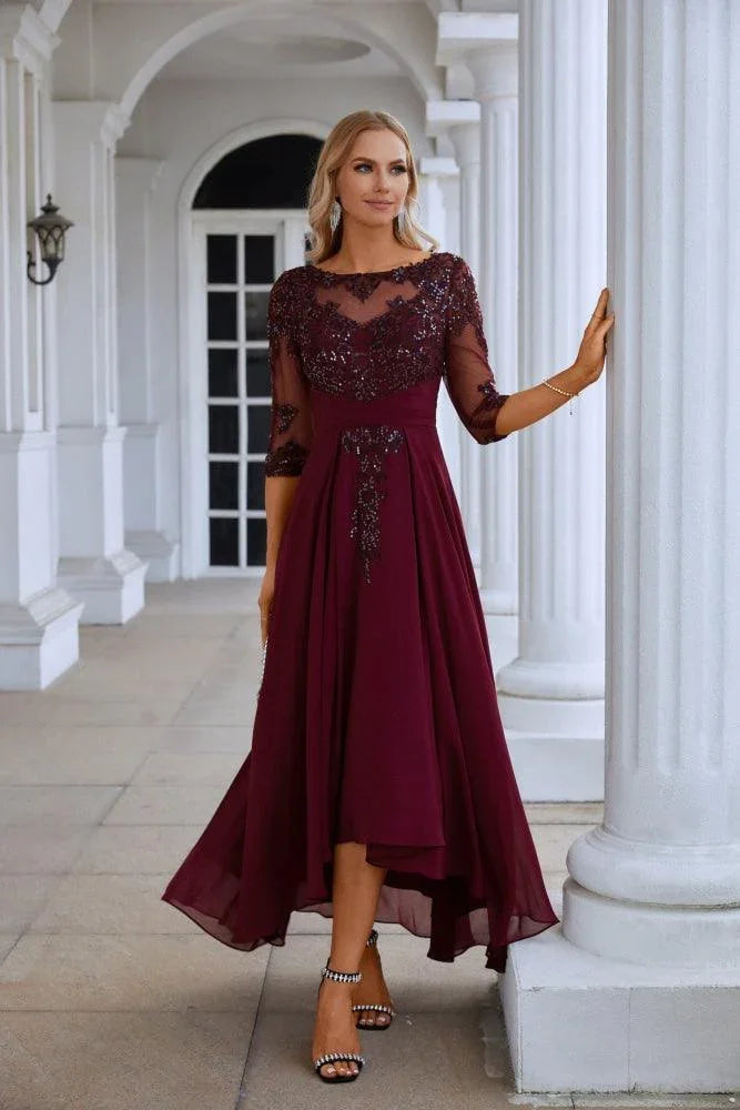 Elegant woman in burgundy beaded mother of the bride dress outside classic white building
