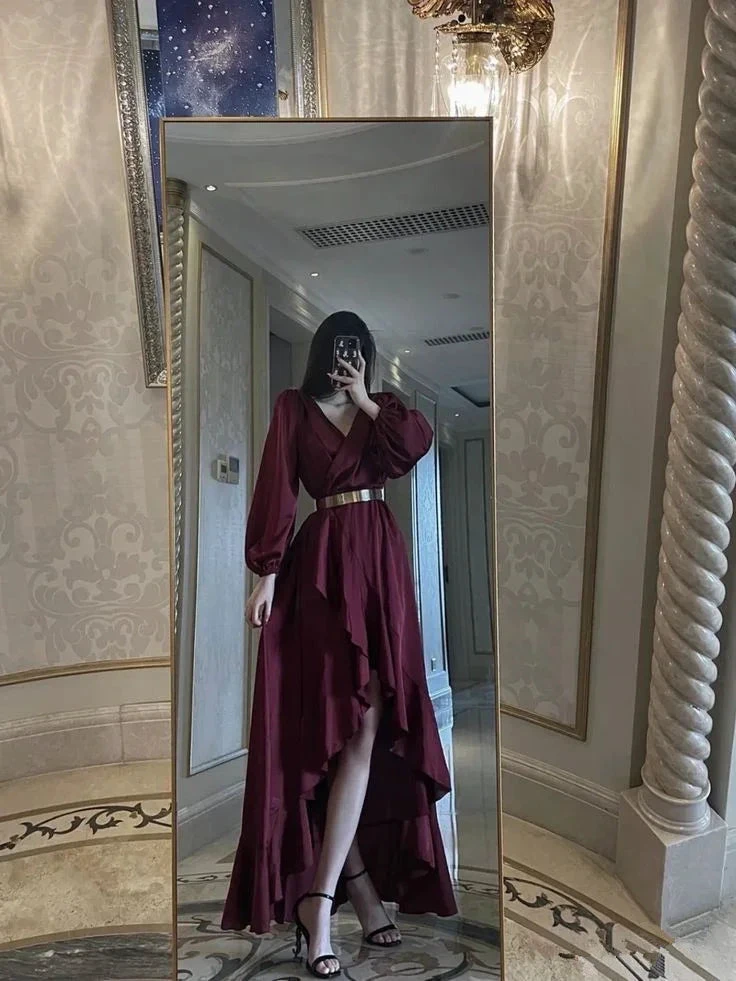Woman in burgundy high-low dress with gold belt posing in luxurious hallway mirror for ZAPDRESS