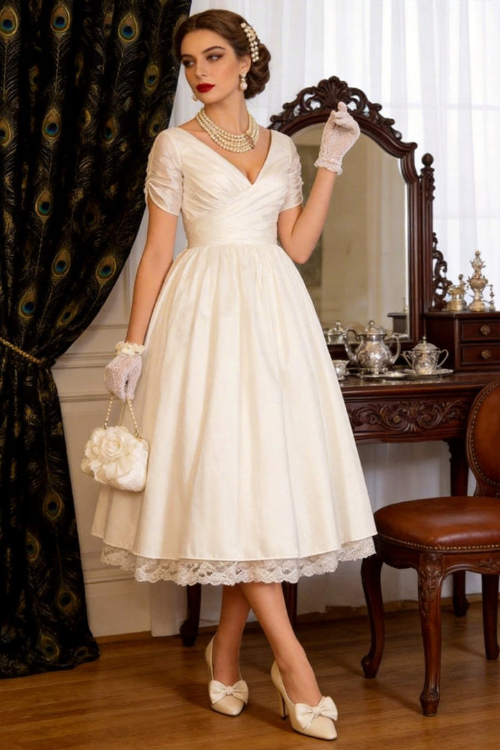 1950s vintage short A-line wedding dress with sleeves, V-neck back, back zipper, tea-length hem with lace trim.