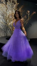 Smiling woman in a flowing purple tulle evening gown at ZAPDRESS, floral backdrop