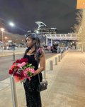 Woman in a black sequin dress holding red and pink roses outside at night, city lights in background, ZAPDRESS fashion