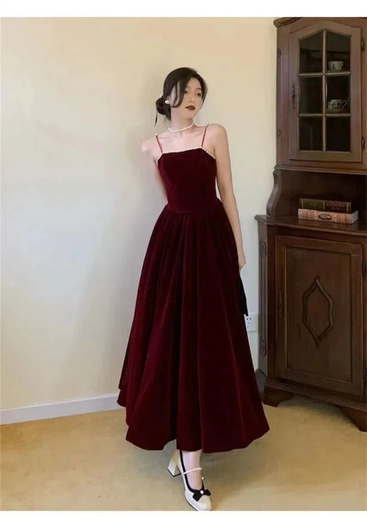 Woman wearing elegant burgundy velvet maxi dress with spaghetti straps, ZAPDRESS fashion