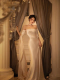 Elegant woman in a satin evening gown by ZAPDRESS standing between curtains on staircase