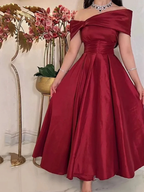 Elegant woman in off-shoulder red satin dress with floral backdrop at ZAPDRESS