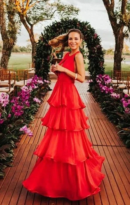Woman in vibrant red tiered dress posing outdoors on wooden walkway with floral arch, ZAPDRESS