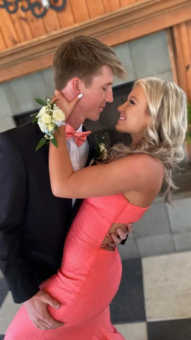Smiling couple posing for prom, woman in sparkly pink gown from ZAPDRESS, man in black suit