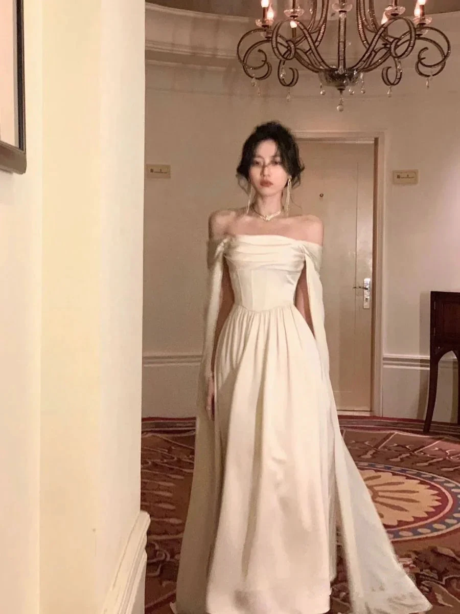 Elegant woman in off-shoulder white evening gown under chandelier at ZAPDRESS