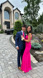 Couple posing in formal attire, woman in pink dress, outside large modern home, ZAPDRESS style