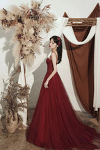 Elegant woman in a red evening gown by ZAPDRESS, posing indoors with dried floral decor