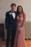 Young couple posing for prom, woman in pink pleated gown, man in black suit with boutonniere