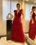 Woman in elegant deep red evening gown with feathered shoulders, standing in modern room, ZAPDRESS fashion