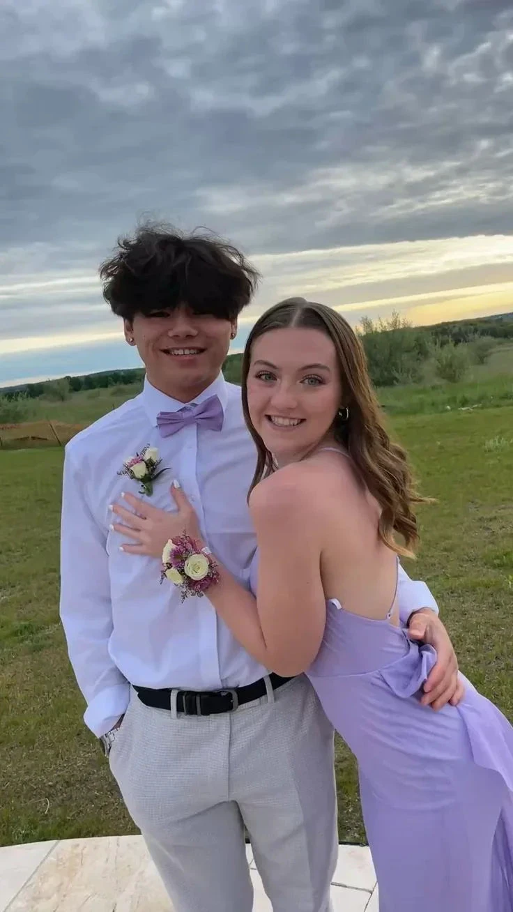 Smiling couple in formal attire posing outdoors, woman in lilac dress from ZAPDRESS