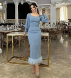 Woman in elegant light blue midi dress with feather hem poses in a luxurious banquet hall, ZAPDRESS