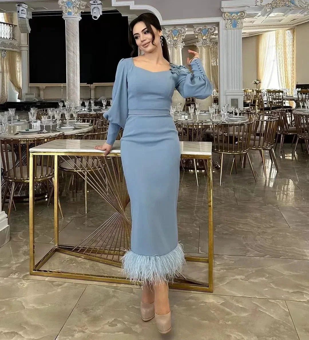 Woman in elegant light blue midi dress with feather hem poses in a luxurious banquet hall, ZAPDRESS