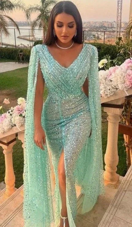 Woman wearing a sparkling aqua blue evening gown with cape sleeves on a terrace, ZAPDRESS