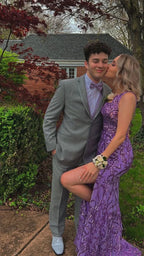 Couple in formal attire, woman in purple sequin prom dress kissing man in gray suit, outdoor garden