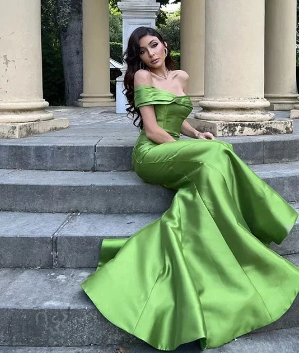 Woman in elegant green off-shoulder evening gown sitting on stone steps, ZAPDRESS fashion