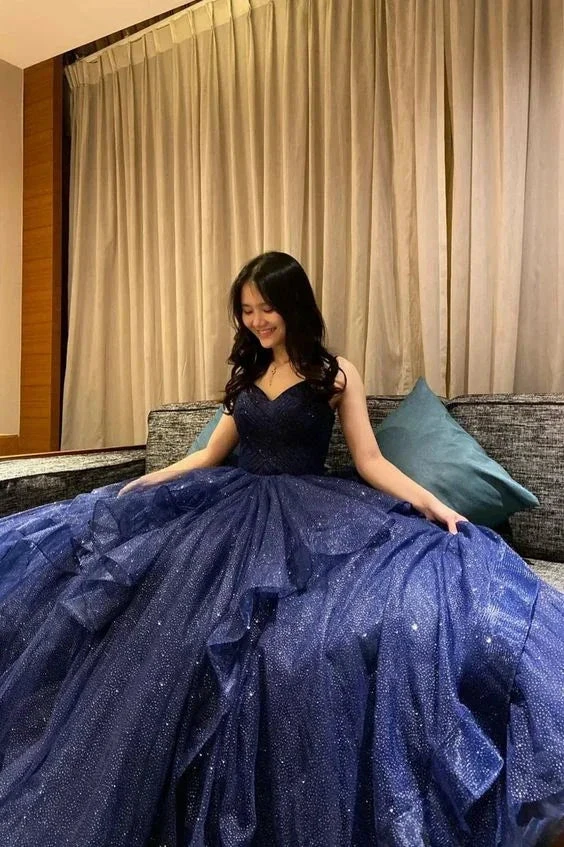 Woman in sparkling navy blue ball gown sitting on a couch, ZAPDRESS formal dress