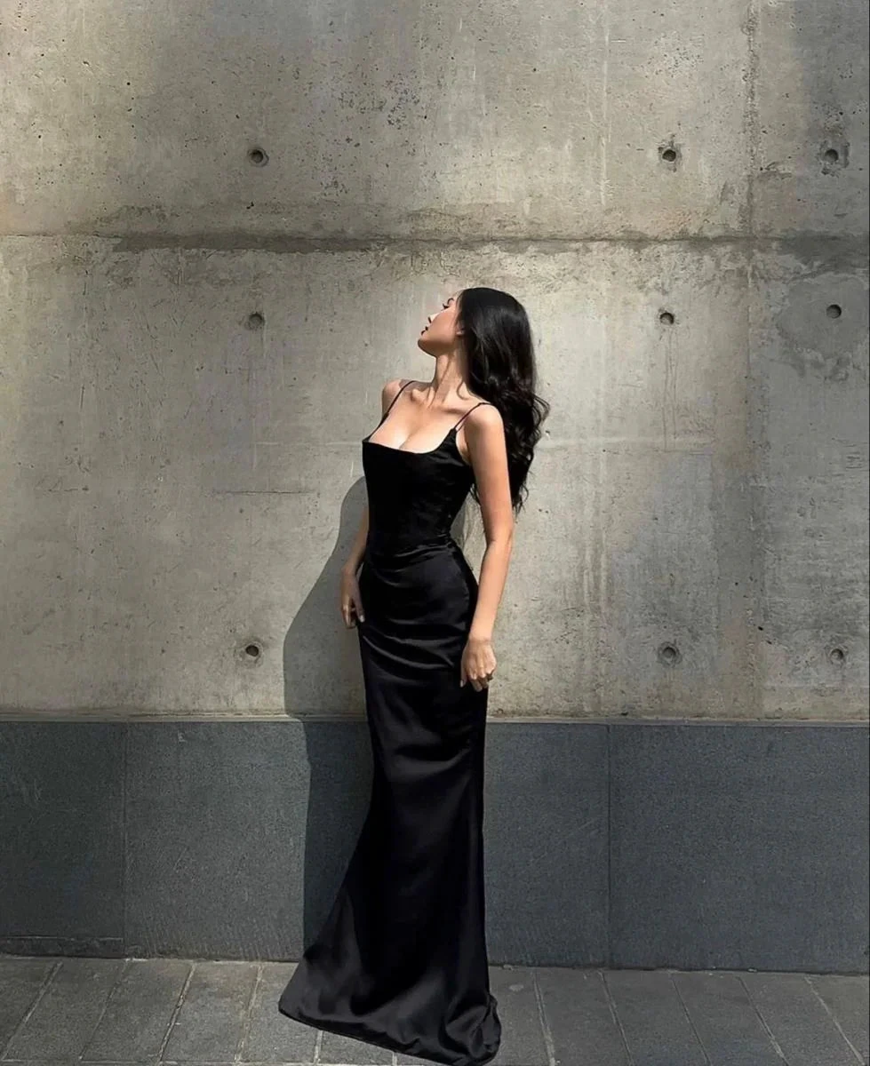 Woman in elegant black evening gown posing against concrete wall, ZAPDRESS fashion