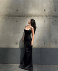 Woman in elegant black evening gown posing against concrete wall, ZAPDRESS fashion