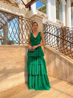 Woman in elegant tiered green dress holding clutch, standing by ornate staircase, ZAPDRESS