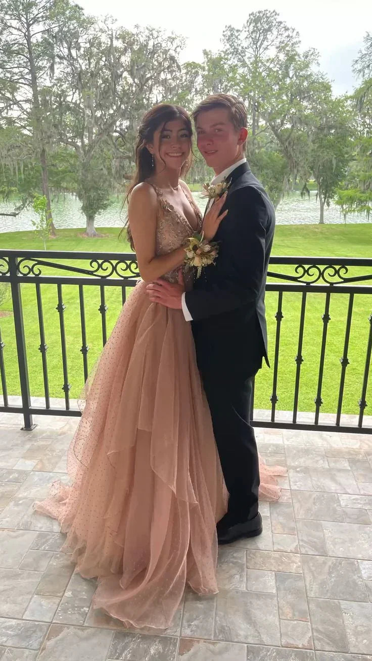 Couple posing on balcony, woman in blush pink formal dress, man in black suit at ZAPDRESS