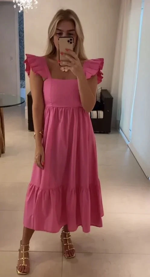 Woman wearing a pink ruffle sleeve dress taking mirror selfie indoors for ZAPDRESS