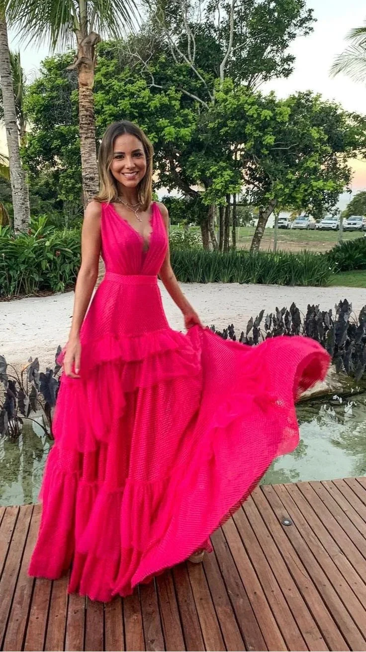 Woman in vibrant pink ruffled maxi dress standing outdoors on wood deck at ZAPDRESS
