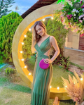 Woman in green dress holding pink clutch, posing outdoors with lights and flowers, ZAPDRESS