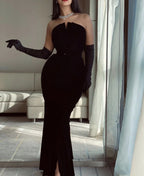 Elegant woman in black strapless evening gown, long gloves, and diamond necklace in modern living room, ZAPDRESS style