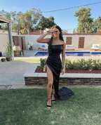 Woman in elegant black evening dress with high slit posing by pool in modern backyard, ZAPDRESS fashion