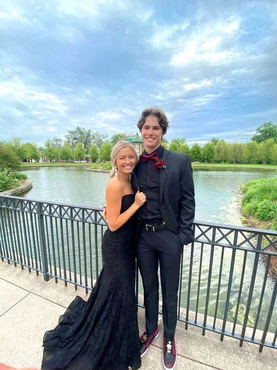 Young couple in formal black attire posing by a lake with elegant railing, ZAPDRESS style