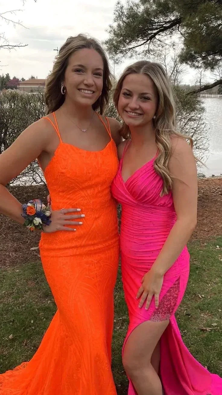 Two women in bright orange and pink formal dresses posing outdoors for ZAPDRESS
