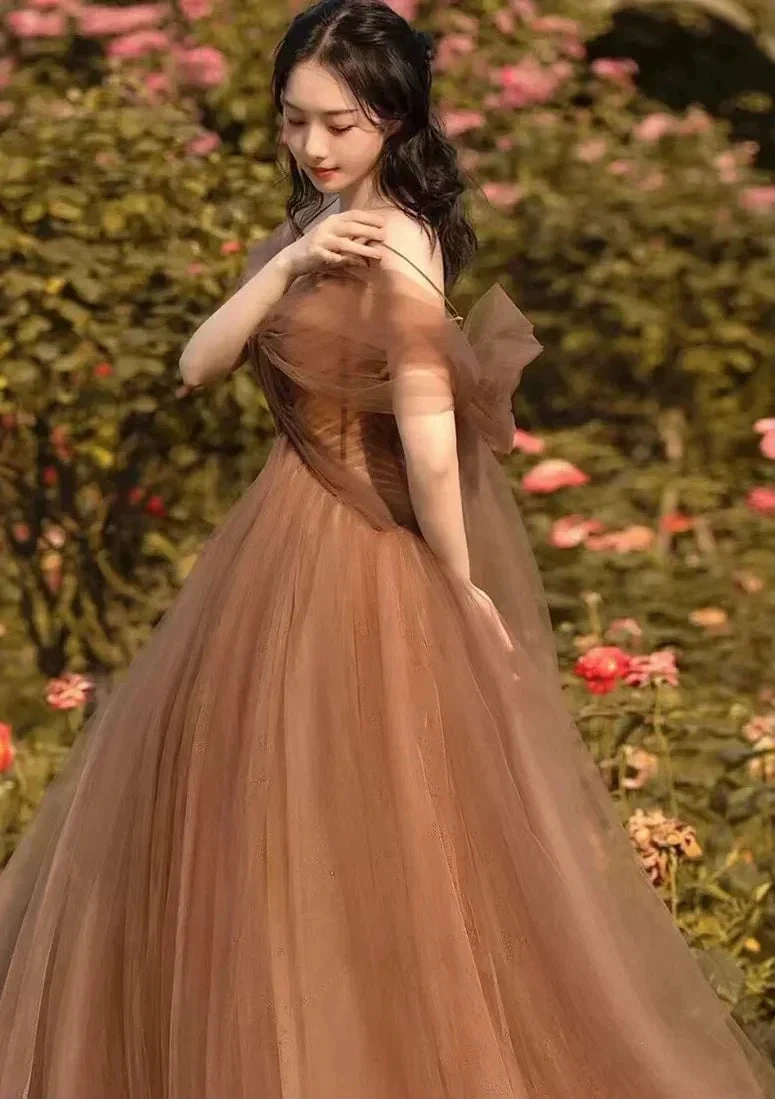 Woman in a flowing brown tulle dress from ZAPDRESS posing outdoors among flowers
