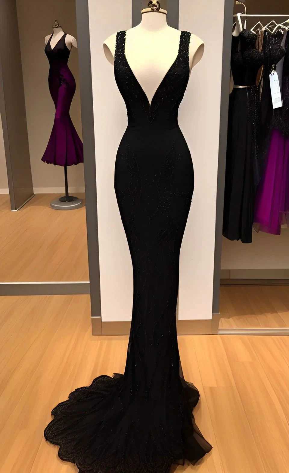 Elegant black evening gown with deep V neckline on mannequin in ZAPDRESS boutique
