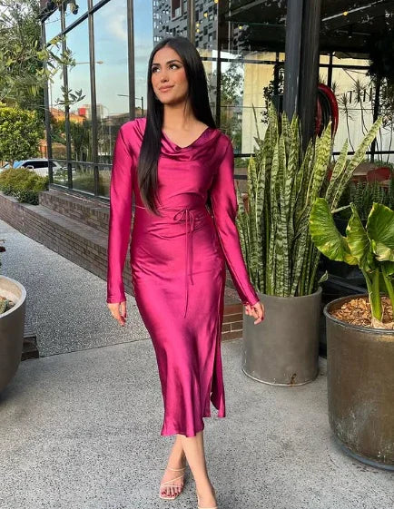 Woman in a shiny magenta satin midi dress from ZAPDRESS, standing outdoors by green plants