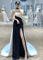 Elegant woman in a black and white evening gown with side slit and bow, in luxury dress boutique