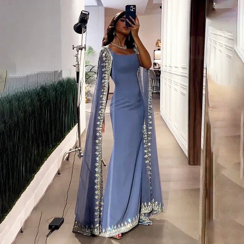 Woman in a blue embroidered evening gown with cape sleeves at ZAPDRESS boutique mirror selfie