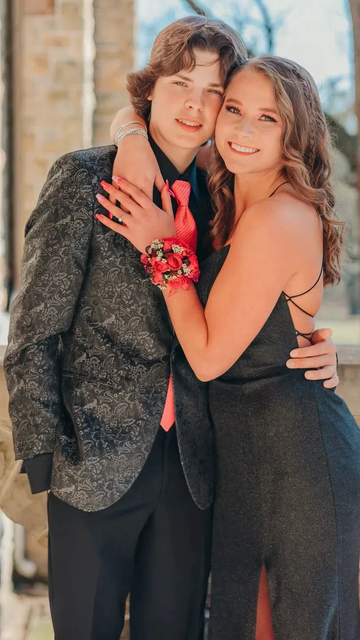 Smiling couple dressed formally, woman in a black dress with red corsage, ZAPDRESS style