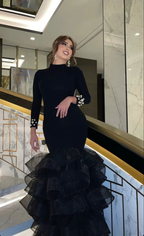 Woman in elegant black ruffled gown with pearl cuffs, standing on marble staircase, ZAPDRESS