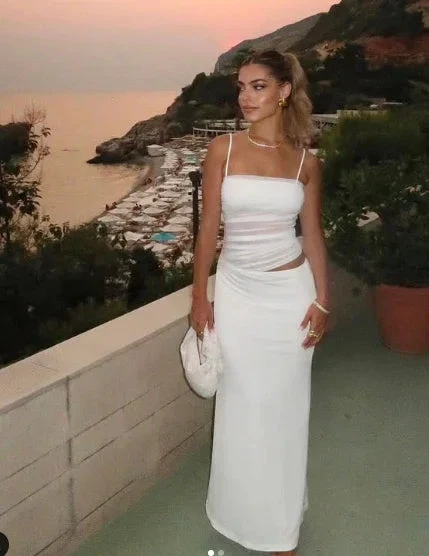 Woman in elegant white dress on a terrace at sunset, beach and hills in the background, ZAPDRESS