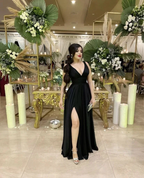 Woman in elegant black evening dress with thigh-high slit at formal event, floral decor, ZAPDRESS