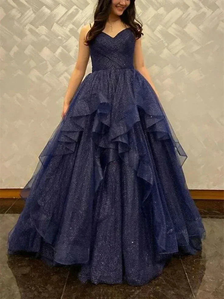 Woman in a sparkling navy blue ball gown from ZAPDRESS, posing indoors against a textured wall.