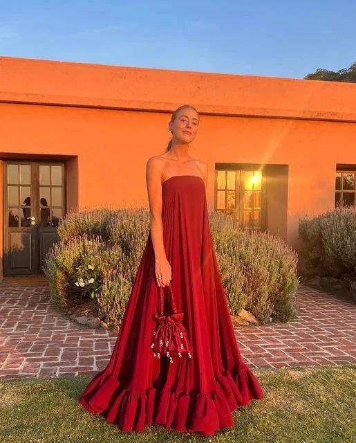 Woman in strapless red maxi dress holding matching bag, sunset outdoors at ZAPDRESS