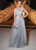 Woman in a sparkly silver evening gown holding a clutch, with floral backdrop at ZAPDRESS.