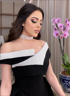 Woman in elegant black and white off-shoulder dress from ZAPDRESS, pearl choker, orchid decor