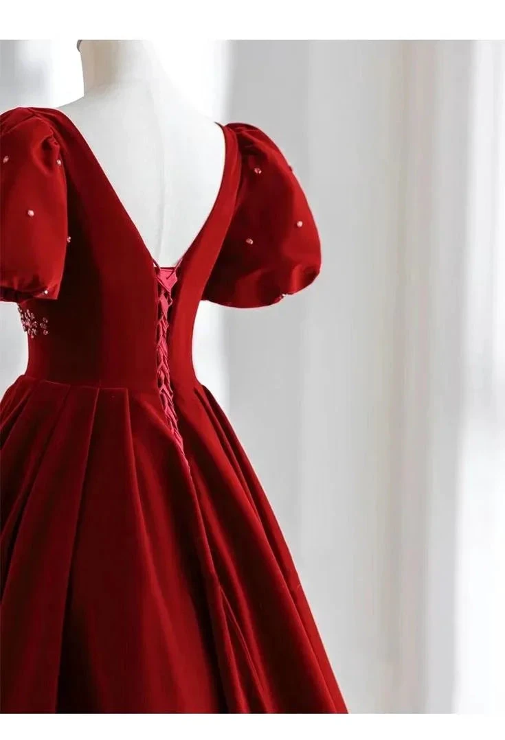Elegant red velvet dress with puff sleeves, pearl accents, and lace-up back on mannequin at ZAPDRESS