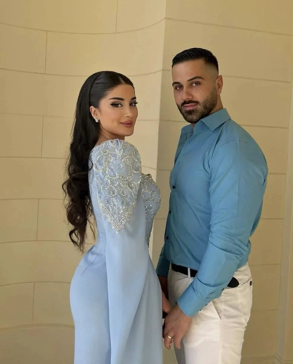 Elegant couple posing in stylish blue outfits, woman in embellished dress by ZAPDRESS