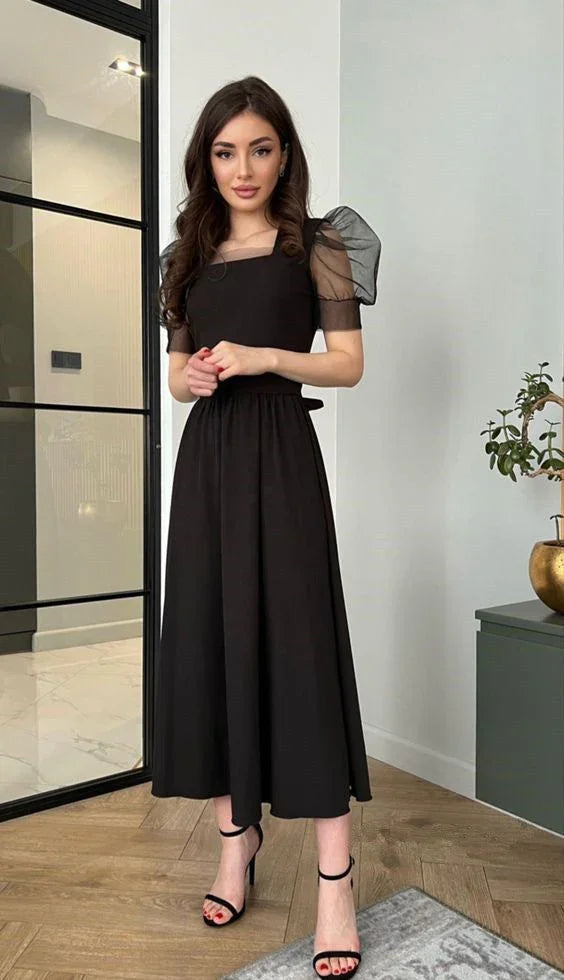 Woman wearing elegant black midi dress with sheer puff sleeves from ZAPDRESS