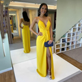 Woman in vibrant yellow evening dress with front slit, posing in boutique for ZAPDRESS